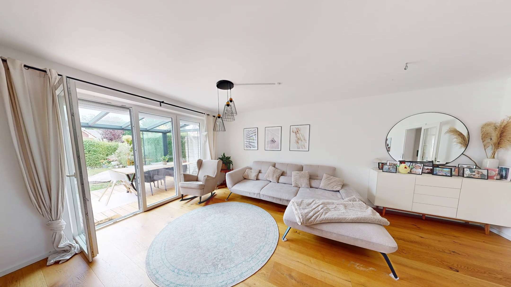 Heller Wohnraum mit Sofa und Blick in den Garten eines Einfamilienhauses