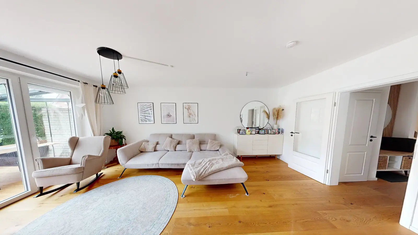 Helles Wohnzimmer mit Sofa und Blick in den Wintergarten im 3D-Rundgang eines Einfamilienhauses